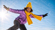 © Milan - Happy woman having fun outdoors in the snow on a sunny winter day. Joyful young person in colorful warm clothes smiling at the camera against a blue sky. Winter vacation and active lifestyle concept