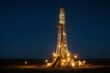 © Mishi Images - Oil drilling rig illuminated at night in remote industrial area under clear sky
