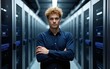 © Lillian - Blond IT trainee standing with arms crossed in server room at industry. High quality