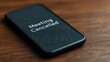 © Peter@studio5 - A mobile phone displays a 'Meeting Cancelled' message on a wooden surface, emphasizing communication and scheduling changes.