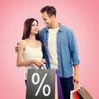 © vgstudio - Holiday sales actions, rebates, discounts offers concept image - happy couple with shopping bags, looking at each other, isolated on vivid rose pink background. Copy space. % sign
