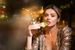 © Volodymyr - Elegant woman eating pizza in night cafe. Sensual woman enjoying food in luxury setting. Woman posing with gourmet pizza slice. Urban nightlife. Sensual expression in city restaurant.