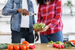 © sofiko14 - A couple prepares a healthy salad together in a bright kitchen, adding dressing to the fresh ingredients.