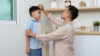 © itchaznong - Family Life: Father measuring son's height at home