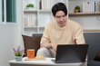 © itchaznong - Work from Home: Young man focused on laptop with snack and drink nearby