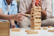 © itchaznong - Family Life: Child playing Jenga with father in a cozy living room