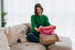 © Maria Vitkovska - Smiling woman unboxing online shopping clothes delivery at home