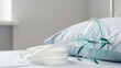 © Maryia - oxygen mask placed neatly on soft medical pillow, clear tubing coiled in organized shape beside mask, minimal clinical bed surface visible