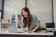 © NINENII - Overjoyed charming excited asian business woman worker using laptop and smartphone working in office, feeling happy.