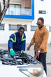 © Roger - African mechanic in blue overalls explains an engine issue to a customer in his workshop