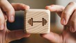 © Funni - Close-up of hands holding a wooden cube with a dumbbell symbol, representing fitness and exercise concepts