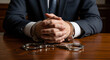 © Cliff - Hands of a man in a business suit in handcuffs at a wooden table, close-up. Concept of fighting corruption