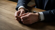 © Cliff - Hands of a man in a business suit in handcuffs at a wooden table, close-up. Concept of fighting corruption