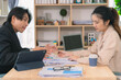 © MrAshi - Asian business couple discussing finances over documents and laptop, explaining details of business growth chart.
