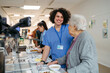 © Halfpoint - Senior woman having lunch with supportive caregiver in community center cafeteria.