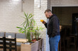 © Astibuk - Man with a beard having coffee in a trendy cafe. He pauses next to the greenery, admiring the plants and taking a moment of rest.