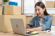 © Pormezz - Young Asian woman owner of small online store packing customer orders in the home office.