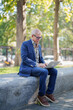 © MINAE - Senior businessman working on laptop outdoors in park