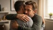© photoplotnikov - Emotional hug between two caucasian men in comforting living room setting