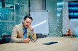 © we.bond.creations - Stressed businessman sitting at a conference table with hand on his face, feeling overloaded and exhausted from work
