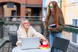 © Iryna - Young women study together outside a cafe in a lively urban area during the afternoon
