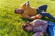 © ADDICTIVE STOCK - Father and daughter lying on grass in sunny park