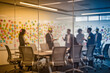 © f_bossa - A group of business professionals collaborating in a modern conference room, viewed through a glass wall with colorful sticky notes on the whiteboard in the background.