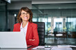 © Stock 4 You - Smiling middle aged business woman using laptop at work office. Professional female executive entrepreneur in red suit working on computer pc at company workplace, looking dreaming aside. Copy space