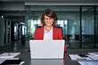 © Stock 4 You - Middle-aged professional specialist latin hispanic business lady in red suit working on laptop pc sitting at desk in office. 40s mature woman using computer technology for analysing work. Copy space