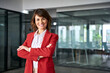 © Stock 4 You - Beautiful hispanic senior business woman in red suit with crossed arms smiling at camera. European or latin confident mature good looking middle age leader female businesswoman in office. Copy space