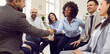 © Studio Romantic - Multinational business team is conducting a meeting in the office, sitting in a circle. Colleagues are shaking hands, symbolizing agreement and teamwork. Collaborative spirit among team members.