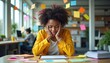 © Pete - Black woman sits at desk with head in hands looking stressed. Colorful sticky notes fly around her in a busy office environment. She is overwhelmed with work tasks and feels pressured.