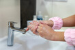 © Iryna - Woman washing hands with soap in bathroom sink. Close-up of a woman lathering her hands with soap under running water at a bathroom sink, promoting hygiene and cleanliness.