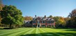 © Pete - Expansive red brick estate with manicured green lawn. Large house features dormer windows and tidy landscaping. Surrounded by mature trees showing autumn colors under clear blue sky.