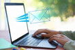 © New Africa - Email notification. Woman using laptop at table, closeup. Letter flying out of screen