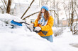© maxbelchenko - A woman in bright jacket clears snow from car windshield in morning in snowy area. Female driver clears snow from car window on sunny winter day. Concepts of transportation, cleaning, and seasonality.