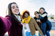 © Xavier Lorenzo - Diverse group of young people having fun taking selfie portrait together outside during winter season