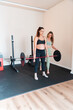 © Manu Padilla/Stocksy - Pregnant woman lifting weights with personal trainer in home gym