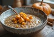 © Sergei - Close-up, high-angle shot of a warm breakfast bowl featuring creamy grain porridge topped with bright orange baked pumpkin cubes, cinnamon, and pepper
