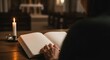 © nuyirdna - Contemplative moment - Person reading a book by candlelight in church.