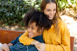© Jimena Roquero/Stocksy - Young couple sitting on bench relaxing and laughing