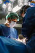© Santi Nuñez/Stocksy - Surgeons performing surgery in brightly lit operating room