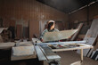 © Dani Nahuel/Stocksy - Woman Lifting Wood Panel onto Table Saw