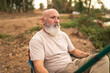 © Lupe Rodriguez/Stocksy - Serene bald man with white beard sitting by fishing rod in nature