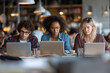© laurent gendre - Diverse students collaborate on laptops in vibrant cafe, fostering innovation and modern learning for dynamic projects and creative collaboration