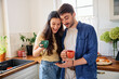 © baranq - Young couple having morning coffee at home using mobile phone together
