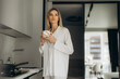 © Roman - Woman enjoying morning coffee in kitchen pajamas