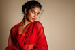 © Suresh Thangavel - Beautiful Indian woman in a monochrome red saree against a muted cream background, fashion-studio lighting, bold contrast, graceful pose