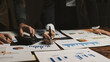 © Crystal - Business team working together at night, analyzing financial reports, using a calculator, and writing notes on documents
