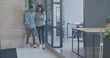 © vectorfusionart - Walking two coworkers checking phone in office near glass wall, wearing blue shirt, copy space